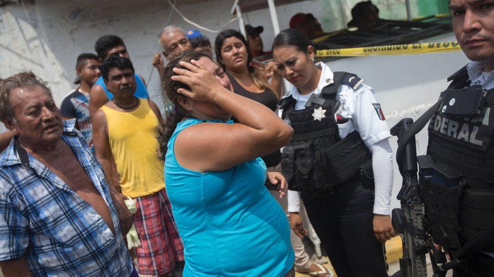 Relatives of five people murdered on a street cry in Acapulco's Icacos neighbourhood