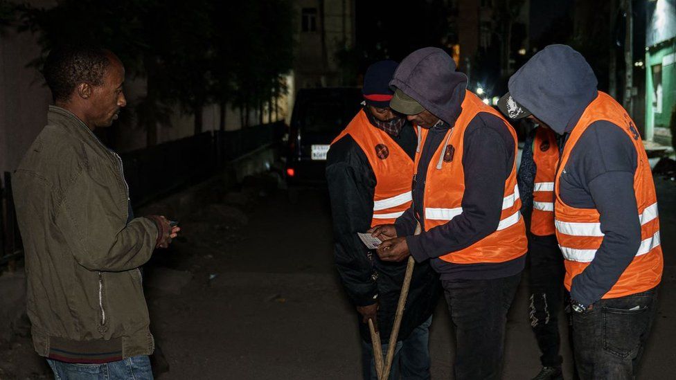 Volunteers check man's identification card as they conduct night patrols in Addis Ababa, Ethiopia, on November 17, 2021.