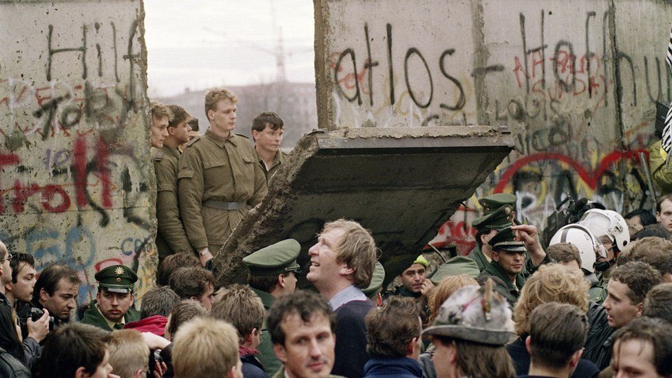 West Berliners crowd in front of the Berlin Wall early 11 November 1989 as they watch East German border guards demolishing a section of the wall.