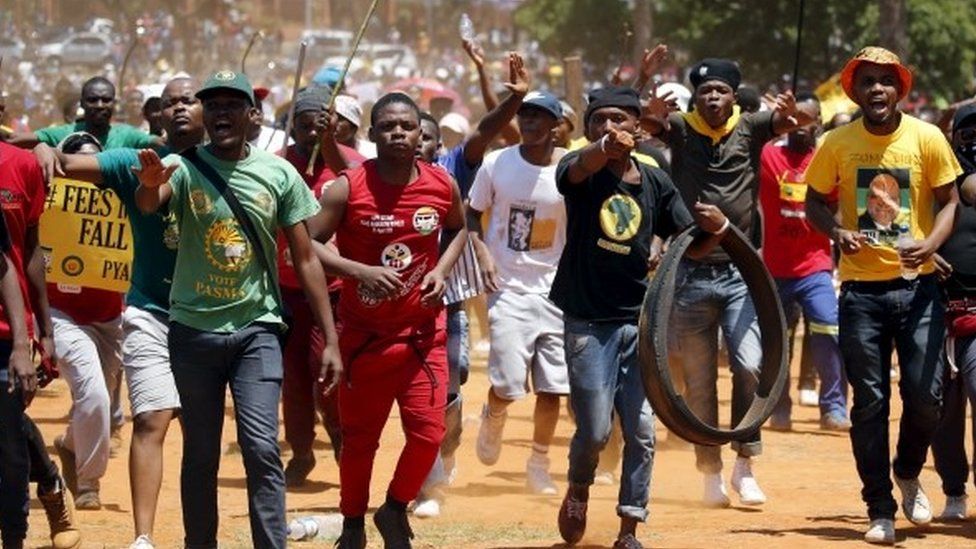 Demonstrators gesture at a photographer during a protest over planned increases in tuition fees outside the Union building in Pretoria, South Africa - 23 October 2015