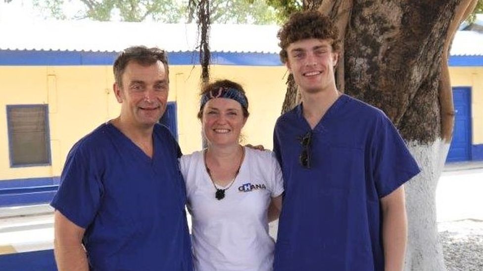 Two men in blue scrubs and woman in white t-shirt