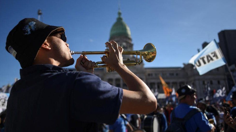 A man plays a trumpet in front of the Argentine congress building during a protest against university cuts