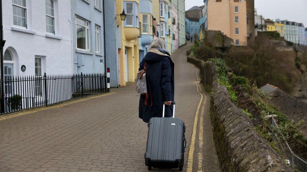 A woman pulling a suitcase in Tenby