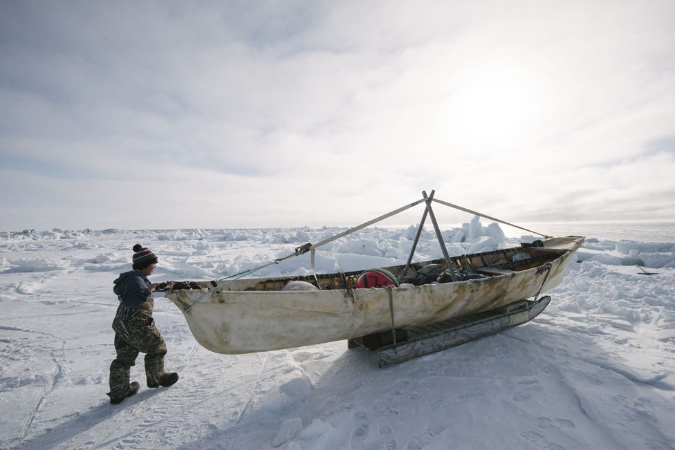 Six-year old Steven Reich examines his father's umiaq, or skin boat used for whaling.