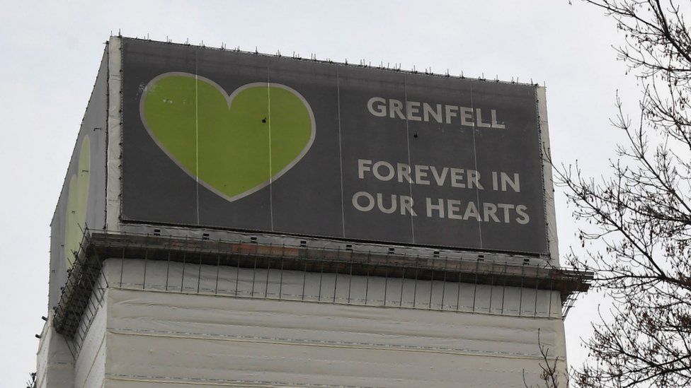 Top of Grenfell Tower wrapped in banner saying "Forever in our hearts"
