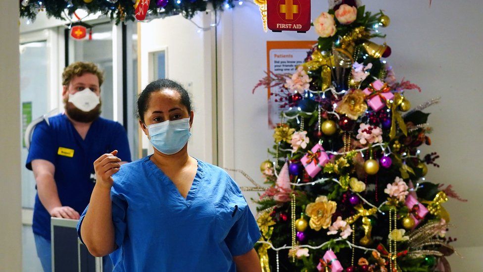 Medical staff walk past a Christmas tree on a ward for Covid patients at King"s College Hospital, in south east London.