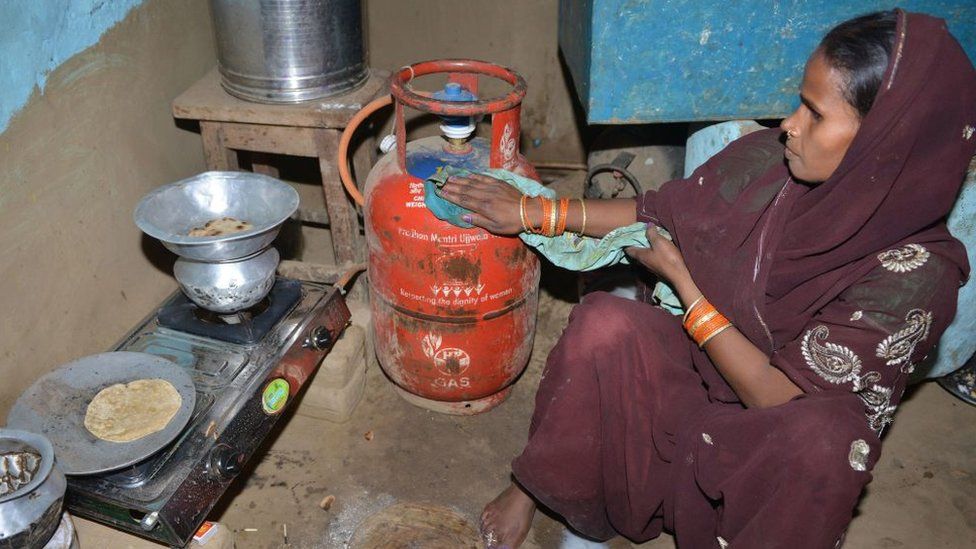 In this photograph taken on April 8, 2019, Indian women Reena Devi (C) cleans a gas cylinder as she prepares food on a gas stove in Nisarpura village on the outskirts of Patna. - Reena Devi says her life changed when she got a cooking gas connection under a programme championed by India's Prime Minister Narendra Modi.