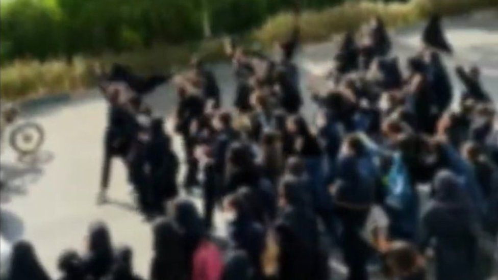 Screengrab of video posted on social media showing protesting schoolgirls blocking a road in Shiraz, Karaj, Iran, while waving their headscarves in the air and chanting "death to the dictator" (3 October 2022)