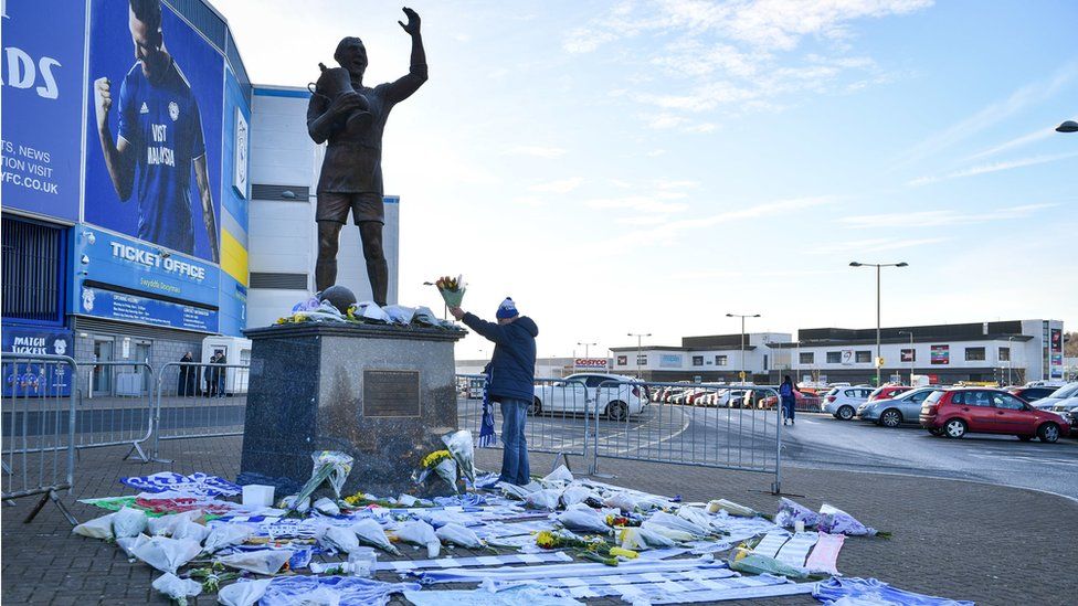 A fan lays flowers by the statue of Cardiff City footballer Frederick Charles Keenor outside Cardiff City Stadium
