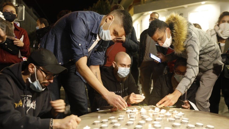Young people light candles near the entrance of the Notre-Dame basilica church in Nice