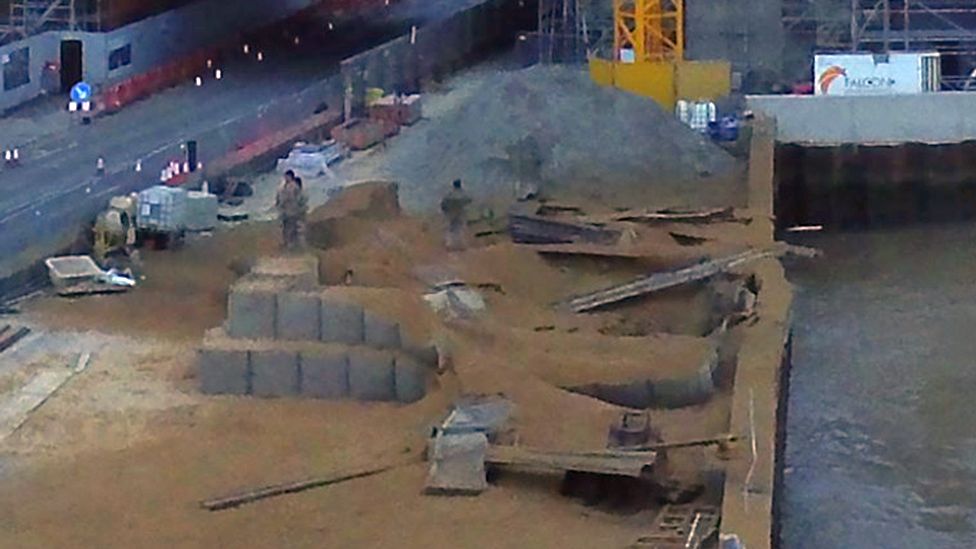 A large crater and warped wall are part of the damage shown in a photo of the aftermath of the blast