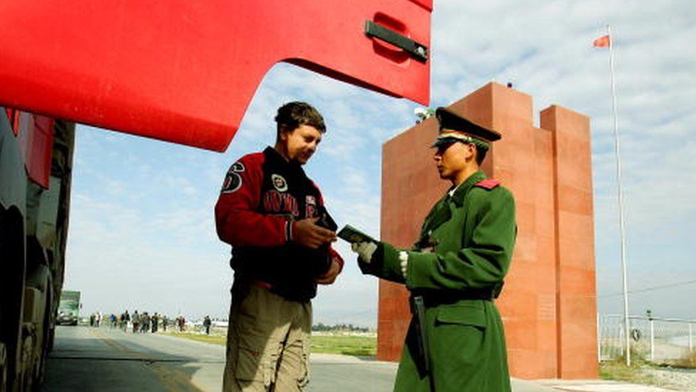 A police officer (R) checks a passport in Xinjiang (File picture October 2005)