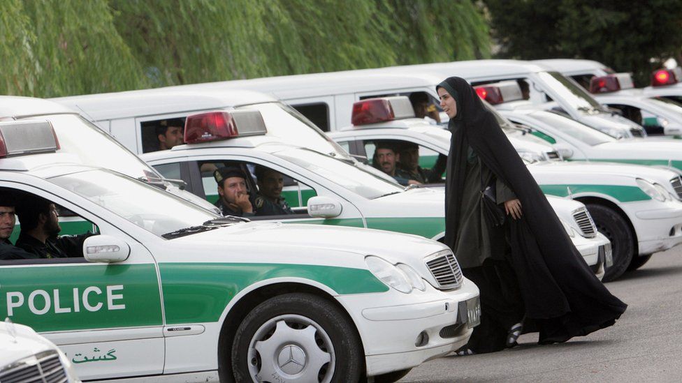 An Iranian morality policewoman walks past police vehicles ahead of a crackdown on women violating Iran's Islamic dress code in Tehran, Iran (23 July 2007)