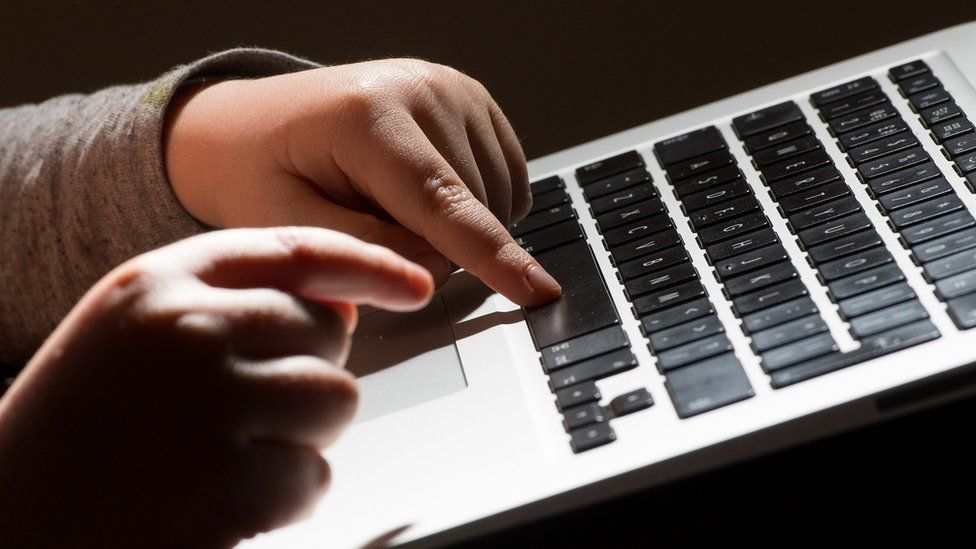 a child typing on a computer keyboard