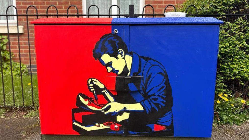 Red and blue painted cabinet with figure of a man wearing a blue shirt sitting in front of a last with a shoe