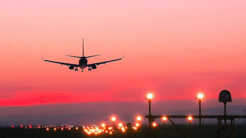 A plane takes off at sunset