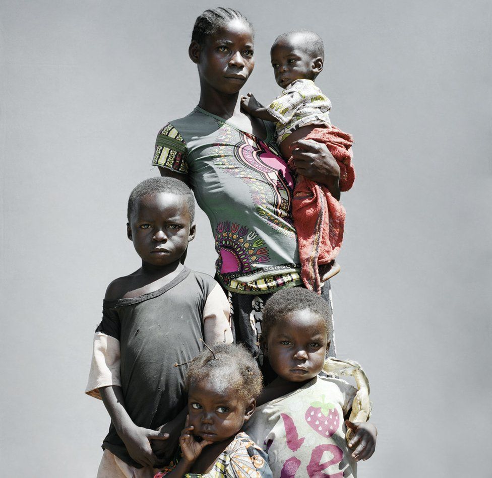 A woman stands with her four children.