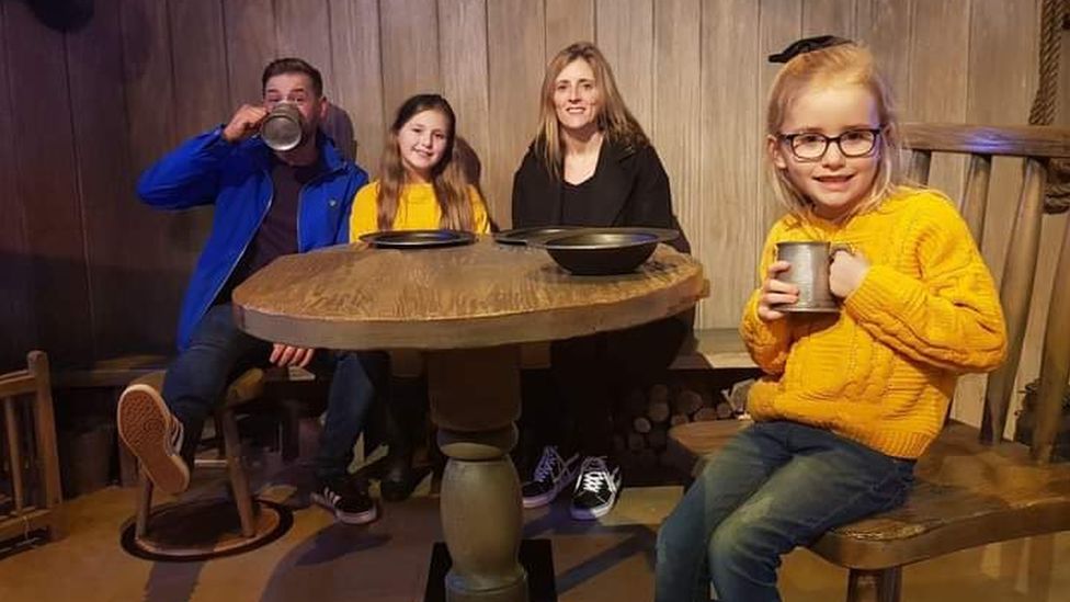 Jamie Davey, his daughter Lillia, partner Kelly and daughter Florrie at sitting at a table.