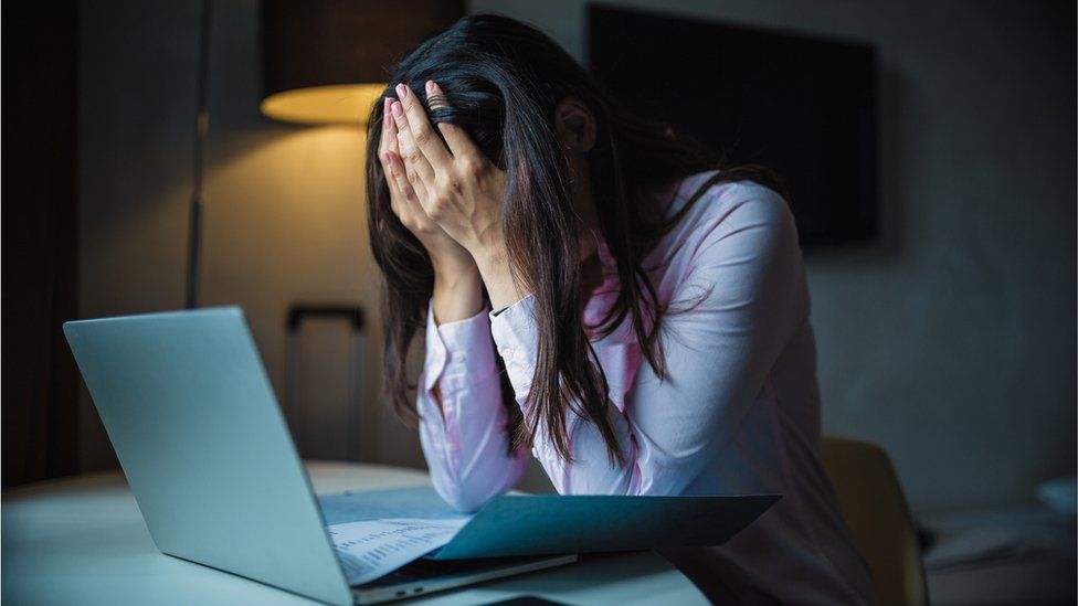 woman with head in hands on laptop