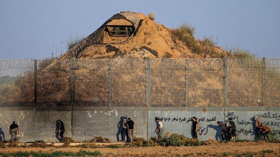 Палестинские протестующие собираются возле израильского военного наблюдательного пункта по другую сторону забора по периметру границы между сектором Газа и Израилем (19 сентября 2023 г.)