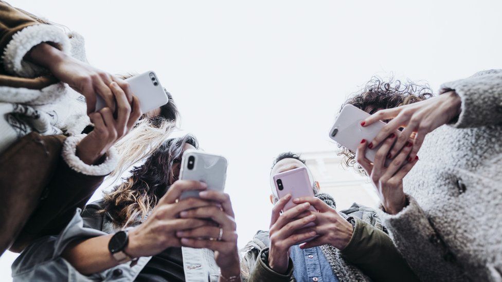 Low-angle shot of teenagers using smartphones