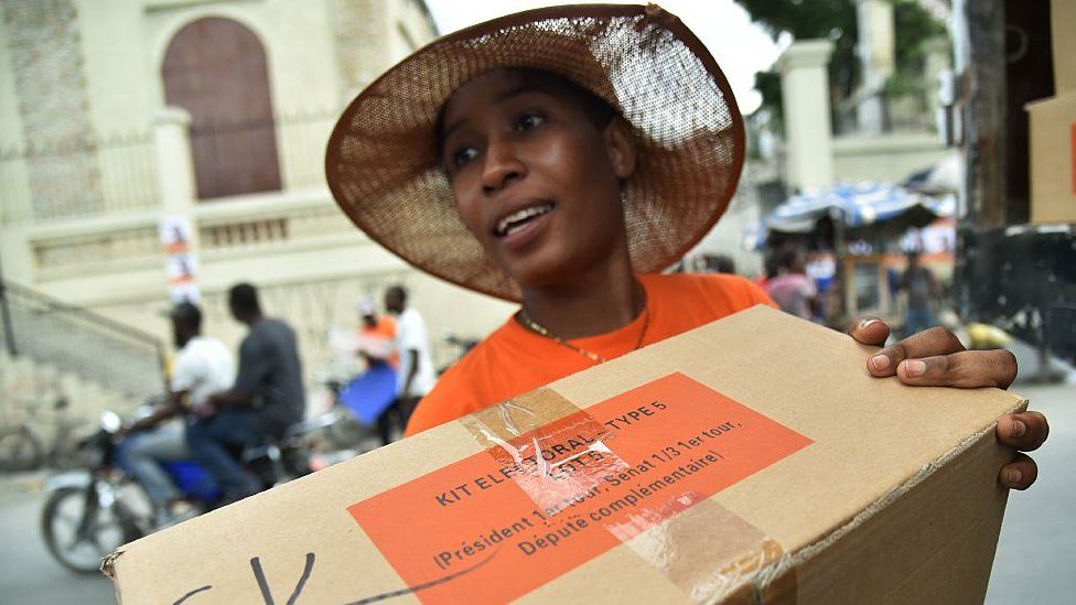 A worker unloads a box with electoral materials delivered by the Provisional Electoral Council (CEP) one day before of the general elections at a polling station in Port-au-Prince, on November 19, 2016
