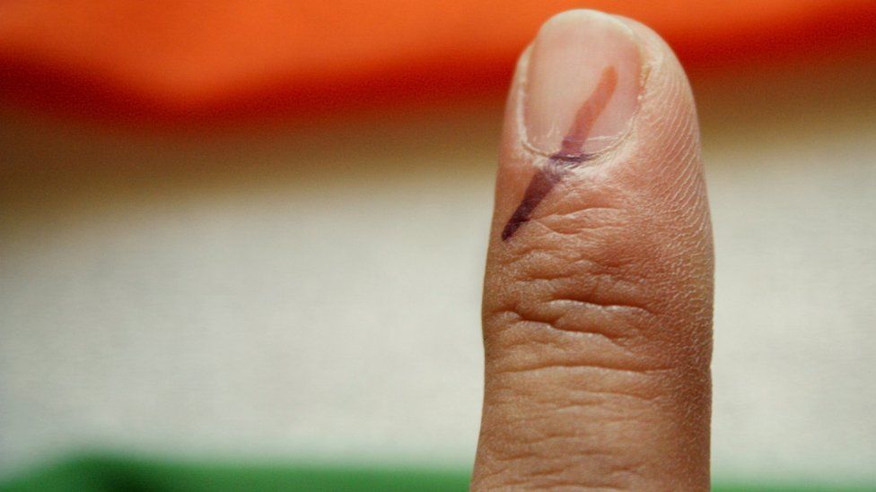 A voter's marked finger is photographed against the Indian flag