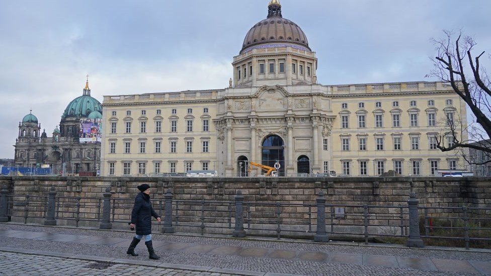 A woman walks past the Berlin Palace prior to the digitally streamed opening of the Humboldt Forum during the second wave of the coronavirus pandemic