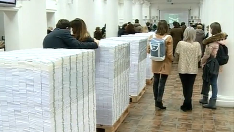 People standing among the piles of fake cash in the library