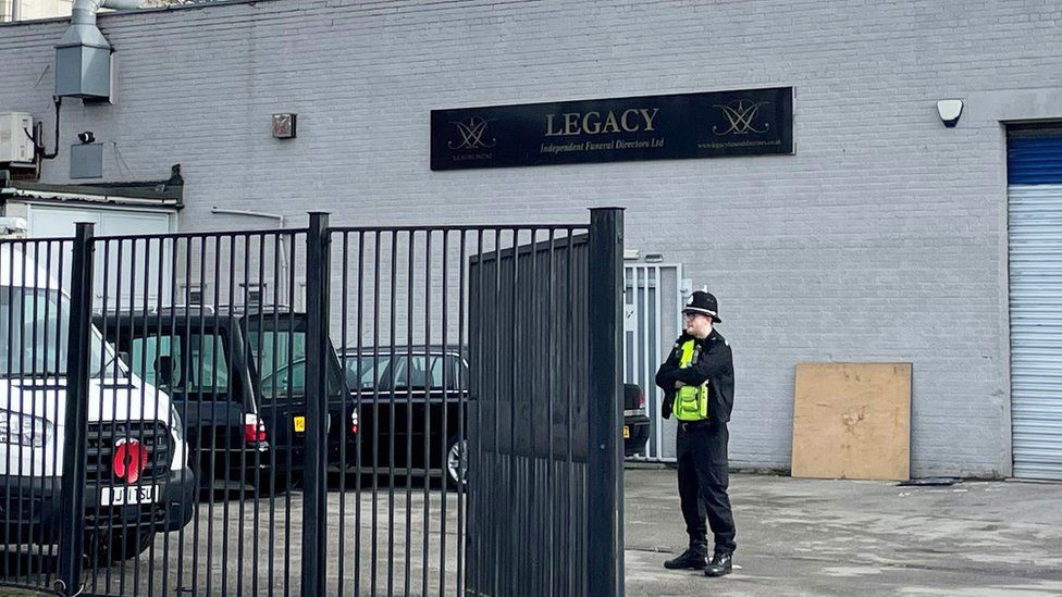 Policeman standing inside Legacy Independent Funeral Directors gated compound