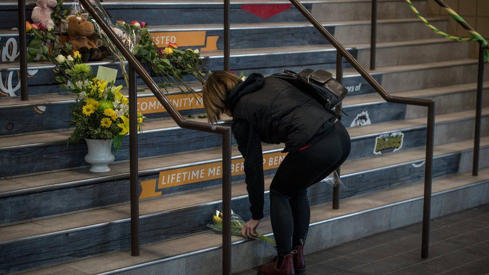 A woman leaves flowers at a memorial for the Humboldt Broncos team at the Elgar Petersen Arena