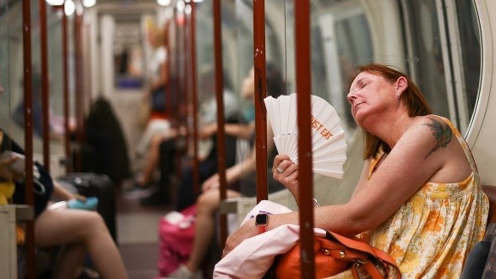 A woman fanning herself on an Underground train