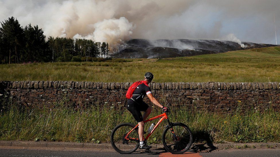 cyclist watches progress of fire from the road