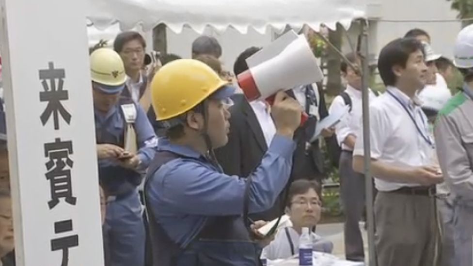 An official in a hard hat holding a megaphone during the drill