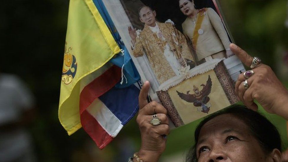 A Thai well-wisher holds up a picture of Thai King Bhumibol Adulyadej and Queen Sirikit as she offers prayers for his recovery at the Siriraj hospital in Bangkok on 6 October 2014.