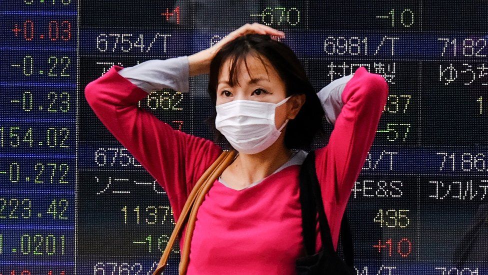 A woman stands in front of a stock quotation board in Tokyo.