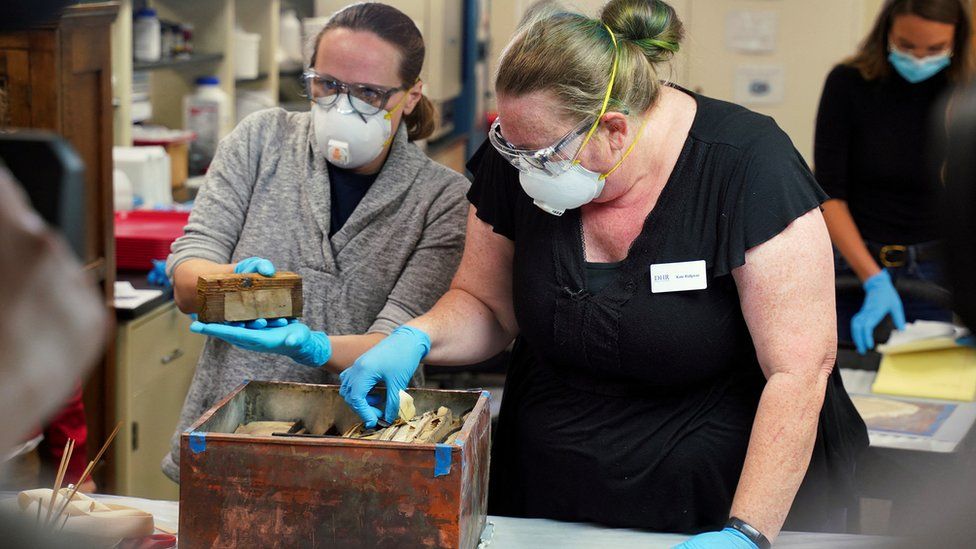 Консерваторы из Департамента исторических ресурсов Вирджинии убирают предметы, найденные в капсуле времени.