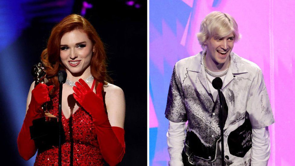 Amouranth is on the left of this composite image - she appears to be accepting and award. She's dressed in a plunging, sparkly sleeveless red gown which almost matches her red hair. She's accessorised with a diamond necklace and elbow-length velvet gloves. On the right, xQc appears in a similar scene, behind a microphone on a stage. He looks relaxed and happy as he leans into the mic. He's wearing an off-white, short-sleeved shirt with an abstract black pattern, over a long-sleeved white tee.