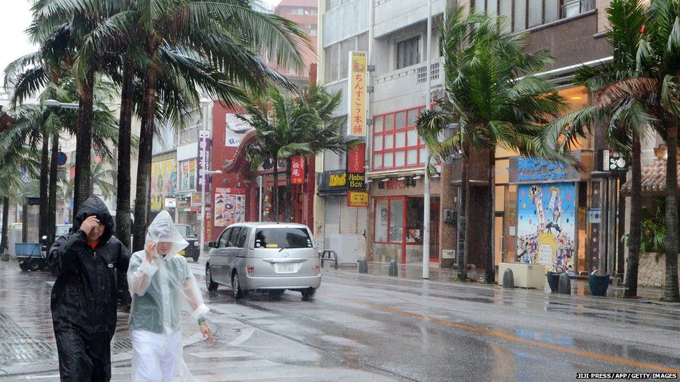 People walk through a street under heavy rains and strong winds, brought on by approaching typhoon