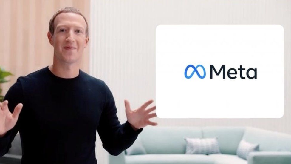 Mark Zuckerberg stands next to the Meta logo