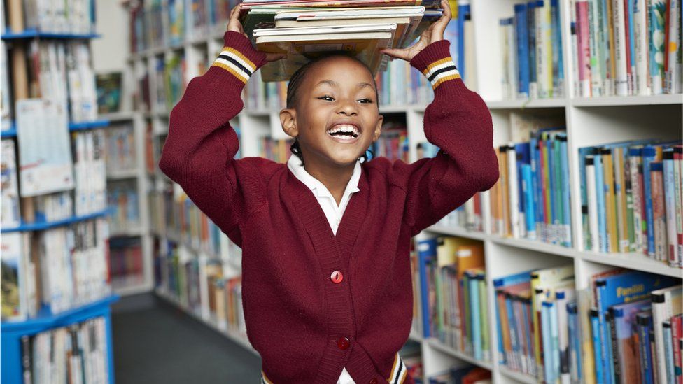 child holding books in a library