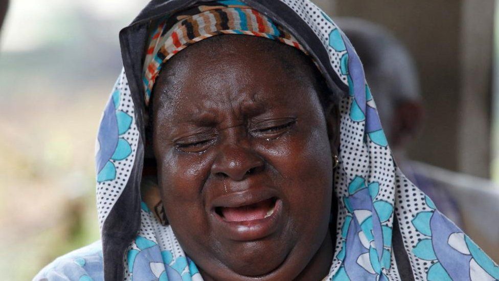 Женщина, чья семья погибла в культе, плачет