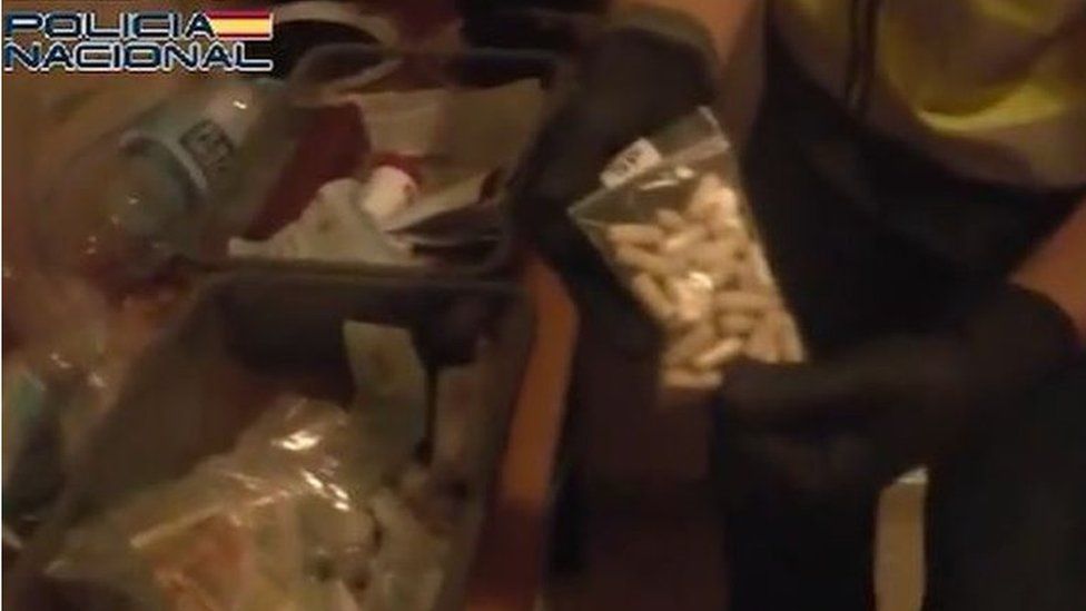 A police officer finds a bag of white pills during a raid of a house