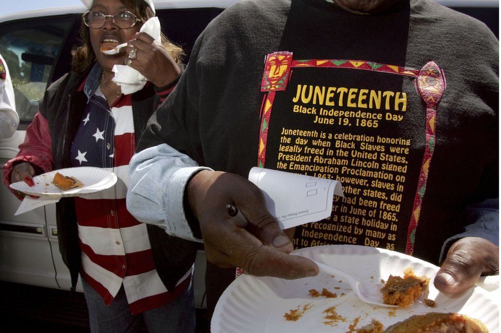 A man in a Juneteenth shirt holds a plate