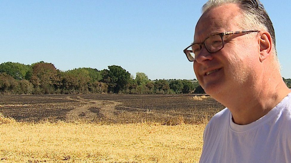 Graeme Cann, a resident of Thorndon, standing in a blackened field after a fire.