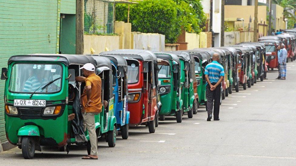 Водители авторикш стоят в очереди на улице, чтобы купить топливо на заправочной станции в Коломбо.