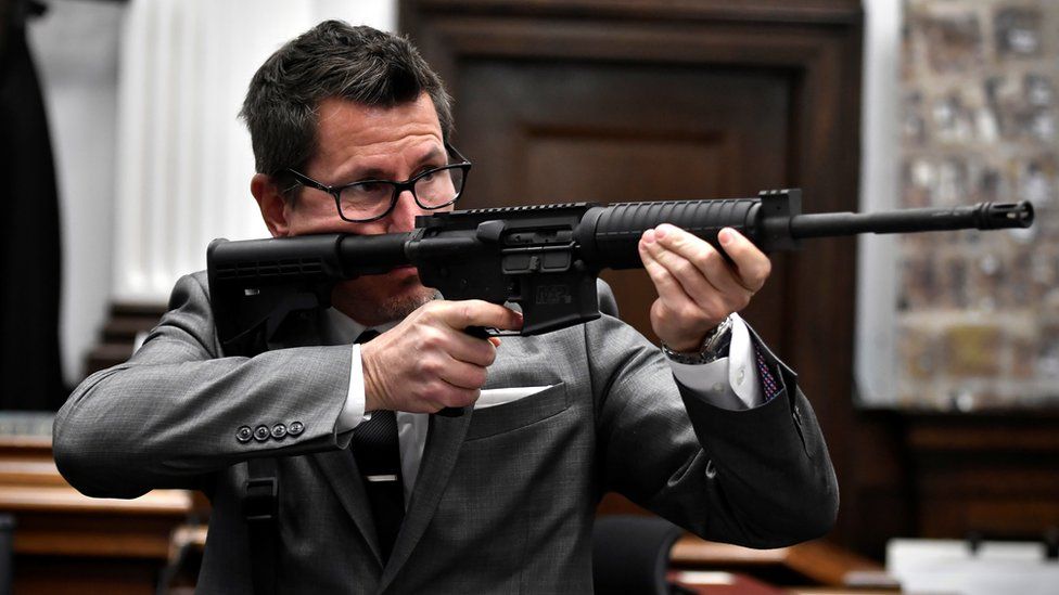 Помощник окружного прокурора Томас Бингер держит пистолет Кайла Риттенхауса, выступая с заключительным аргументом штата в суде по делу Кайла Риттенхауса Здание суда округа Кеноша, Висконсин