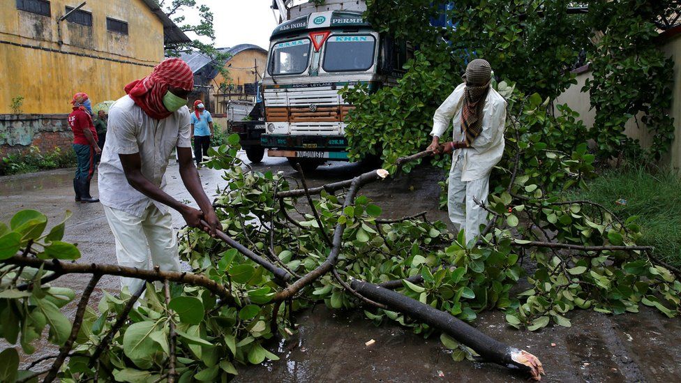 Rescue workers cut tree branches that fell on a truck trailer after heavy winds caused by Cyclone Amphan, in Kolkata, India, May 20, 2020.