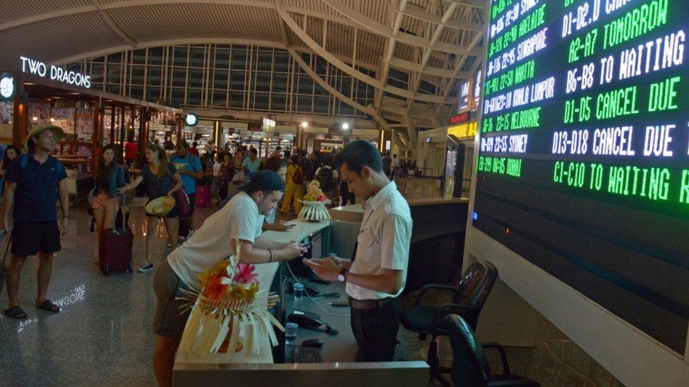 Passengers wait for flight information at Ngurah Rai airport in Bali
