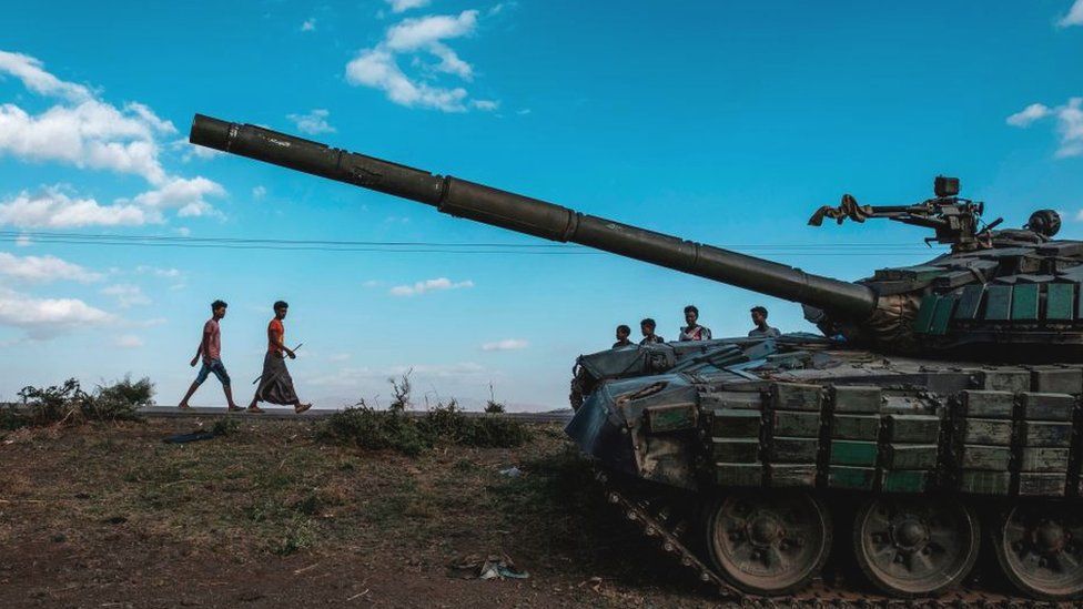 Young people walk next to an abandoned tank belonging to Tigrayan forces south of the town of Mehoni, Ethiopia - 11 December 2020